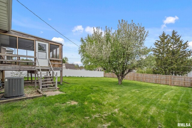 view of yard with central air condition unit, a fenced backyard, a sunroom, and stairs