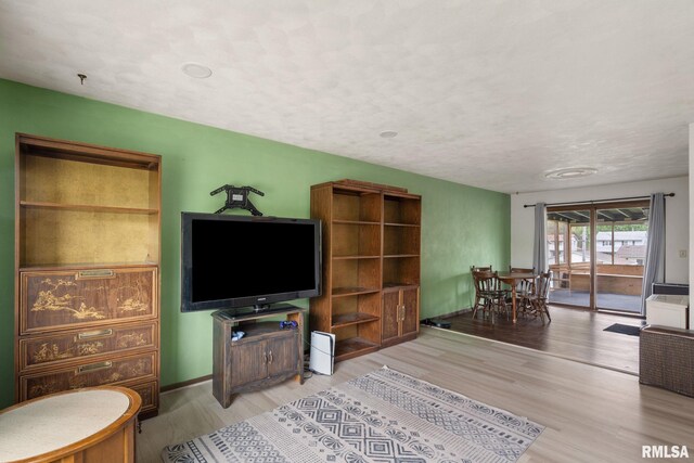 living room featuring a textured ceiling, baseboards, and wood finished floors