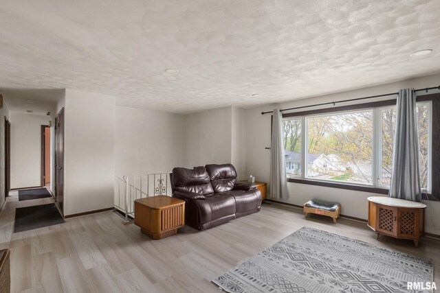 living area featuring a textured ceiling, baseboards, recessed lighting, and light wood-style flooring