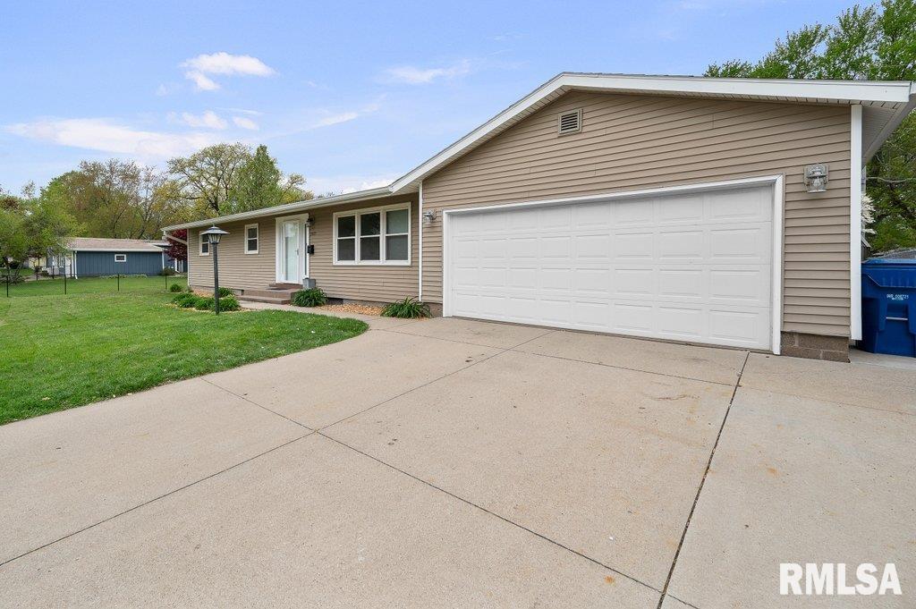 single story home featuring concrete driveway, a front lawn, and a garage