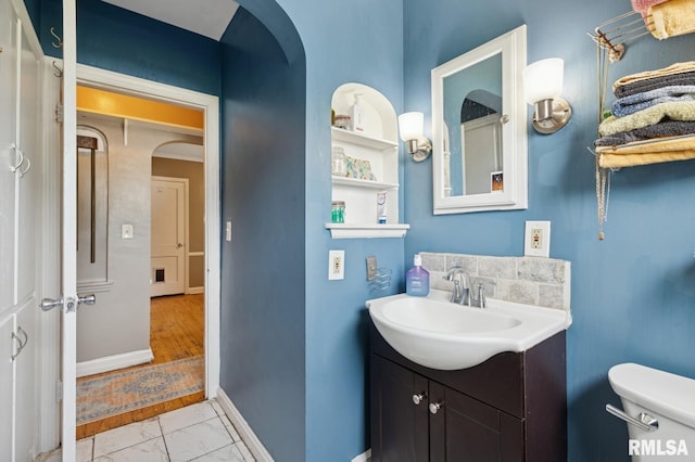 bathroom with toilet, baseboards, marble finish floor, and vanity