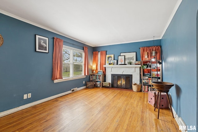 living room with visible vents, crown molding, a brick fireplace, wood finished floors, and baseboards