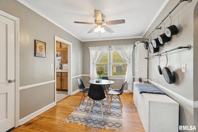 dining space with crown molding, a ceiling fan, baseboards, and light wood finished floors