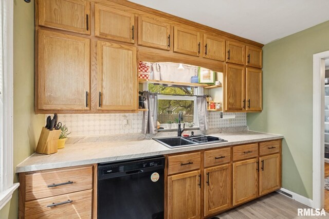 kitchen with open shelves, a sink, light wood finished floors, black dishwasher, and decorative backsplash