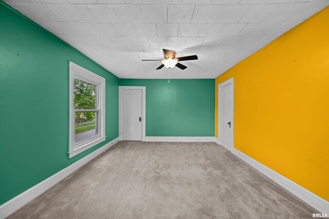 carpeted spare room with a ceiling fan and baseboards