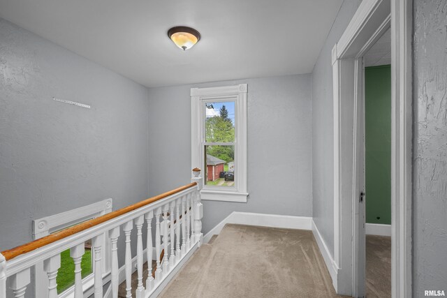 corridor featuring baseboards, carpet, and an upstairs landing
