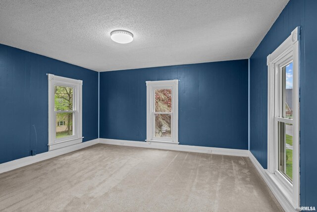 empty room with carpet floors, a textured ceiling, and baseboards