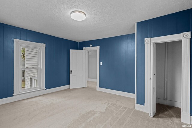 unfurnished bedroom with baseboards, a textured ceiling, and carpet