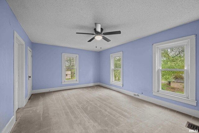 unfurnished bedroom with baseboards, multiple windows, carpet floors, and visible vents