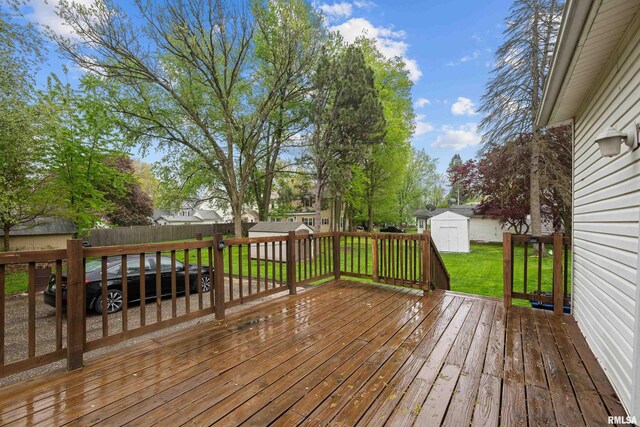 wooden terrace with a storage unit, a fenced backyard, a lawn, and an outbuilding