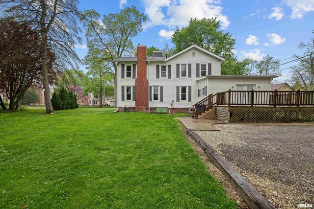 back of property featuring a yard, a deck, and a chimney