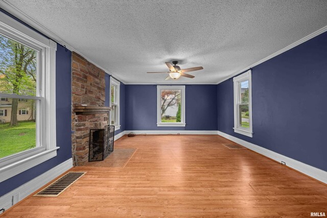 unfurnished living room with ceiling fan, a textured ceiling, visible vents, wood finished floors, and baseboards