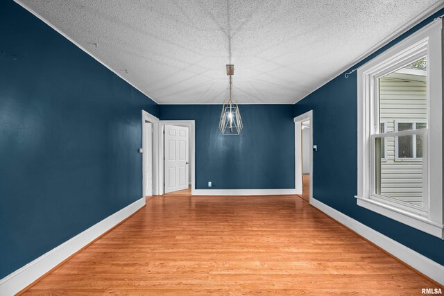 unfurnished room featuring baseboards, a textured ceiling, a chandelier, and light wood-style flooring