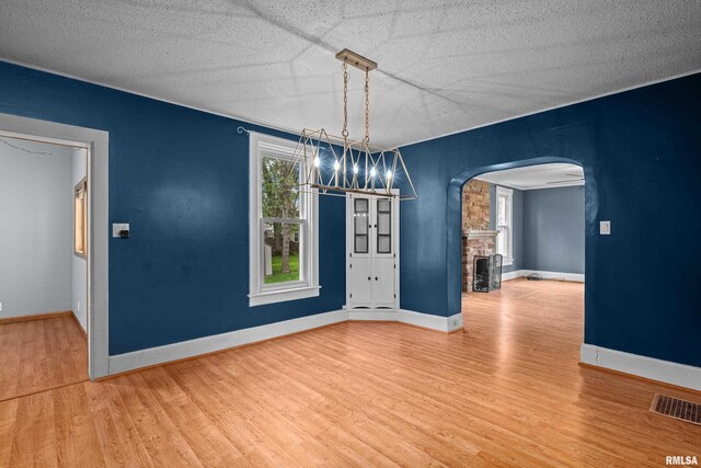 unfurnished dining area with arched walkways, baseboards, wood finished floors, and visible vents