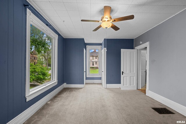 spare room with carpet floors, plenty of natural light, a ceiling fan, and visible vents
