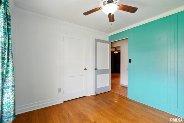 unfurnished bedroom with ceiling fan, light wood finished floors, baseboards, ornamental molding, and a closet