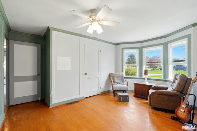 living area featuring crown molding, a wealth of natural light, and light wood-type flooring