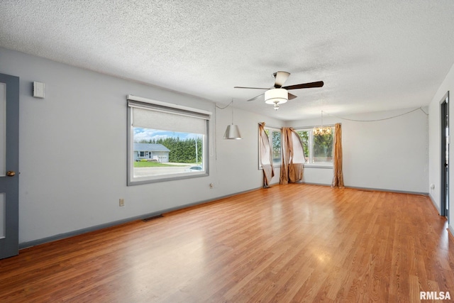 empty room with ceiling fan, a textured ceiling, visible vents, light wood-type flooring, and baseboards