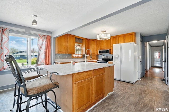 kitchen featuring light countertops, a textured ceiling, tasteful backsplash, a sink, and stainless steel appliances