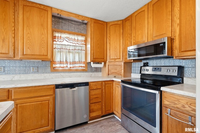 kitchen with light countertops, a textured ceiling, appliances with stainless steel finishes, and tasteful backsplash