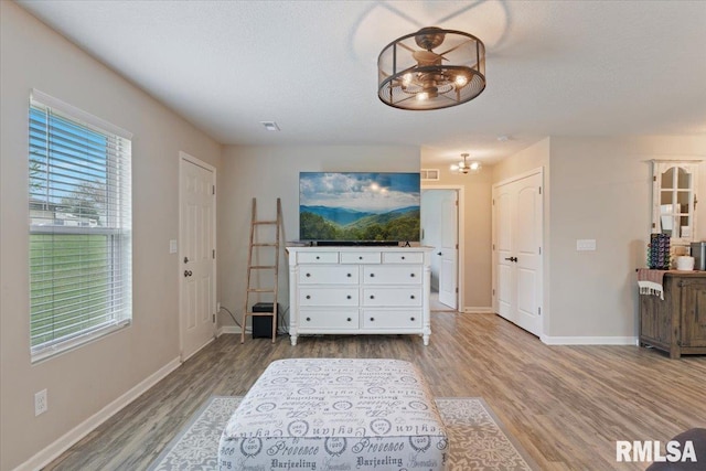 living room featuring baseboards, light wood-style flooring, a notable chandelier, and visible vents
