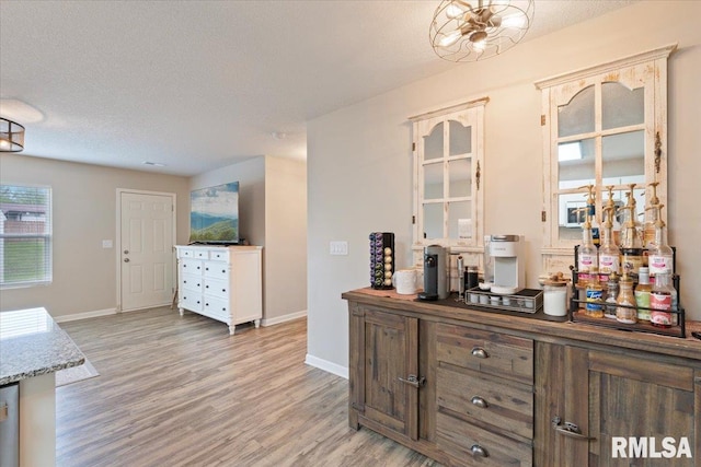 interior space with a textured ceiling, baseboards, and light wood-style flooring