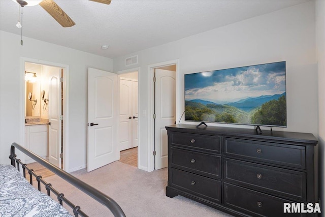 bedroom featuring visible vents, light carpet, baseboards, a ceiling fan, and ensuite bath