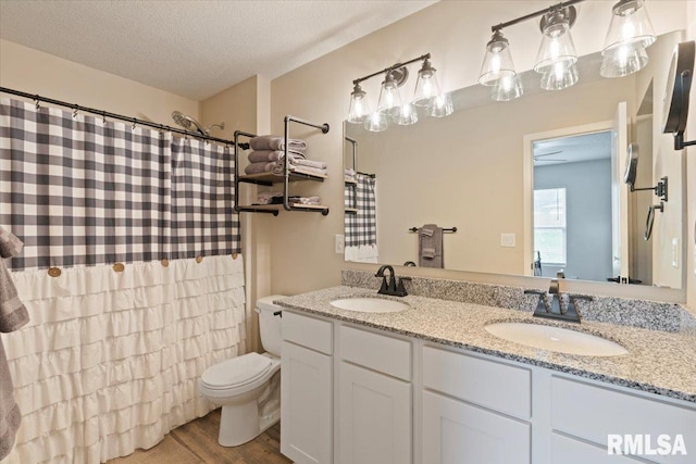 full bathroom with toilet, a textured ceiling, a sink, and wood finished floors