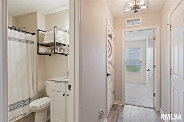 bathroom with visible vents, vanity, wood finished floors, toilet, and baseboards