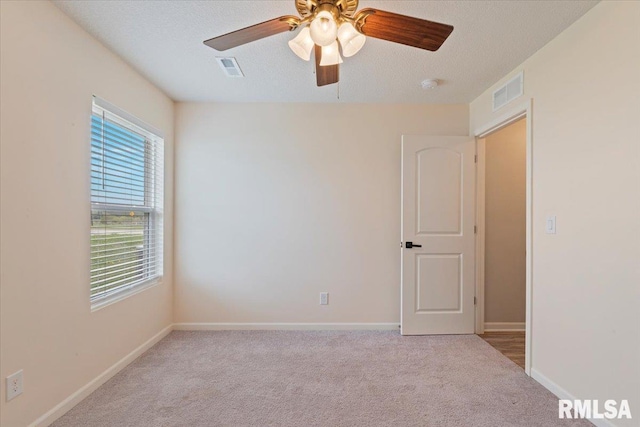 spare room featuring visible vents, a ceiling fan, and carpet