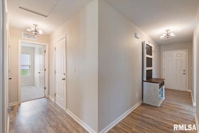 corridor with a chandelier, wood finished floors, and visible vents