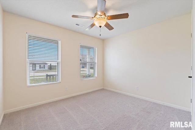 carpeted spare room with a ceiling fan, baseboards, and visible vents