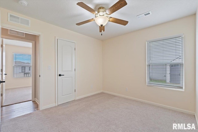 spare room featuring carpet flooring, ceiling fan, visible vents, and baseboards