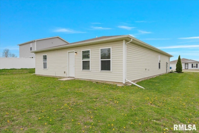 back of property with a lawn and fence