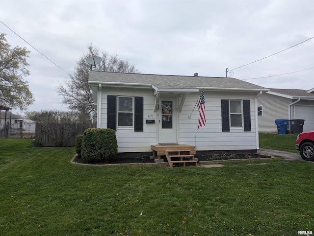 bungalow-style house with a shingled roof, a front yard, and a garage