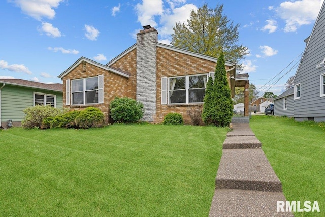 view of front facade featuring brick siding, a front yard, and a chimney