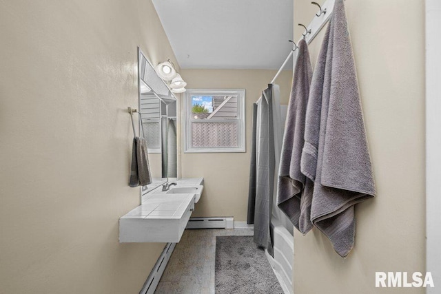 bathroom with baseboards, a baseboard heating unit, a sink, and shower / tub combo with curtain