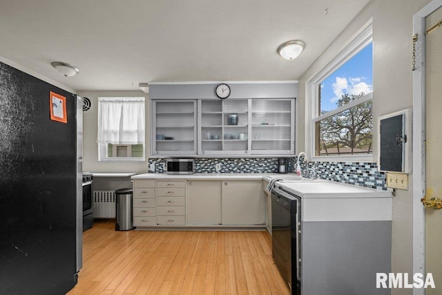 kitchen with a sink, light countertops, tasteful backsplash, and light wood-style floors