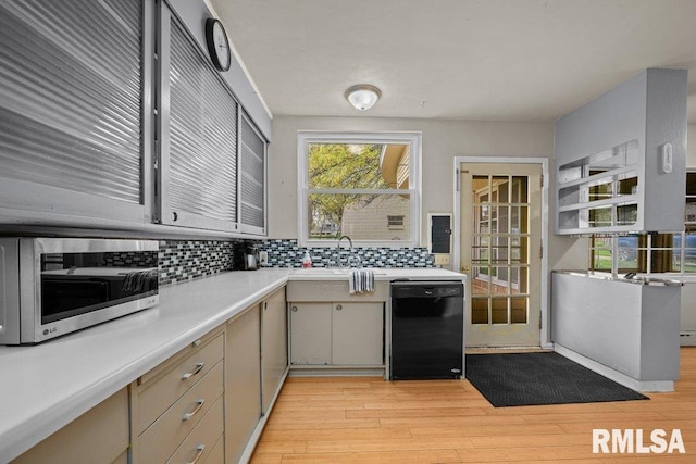 kitchen featuring a sink, decorative backsplash, stainless steel microwave, and black dishwasher