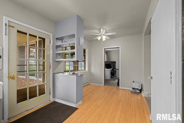 interior space with wood finished floors, a ceiling fan, baseboards, and a baseboard heating unit