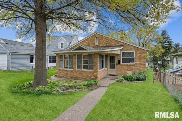 view of front of property with fence, a front lawn, and brick siding