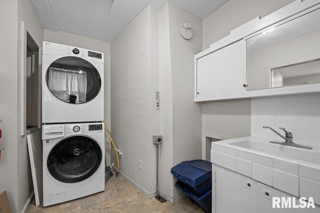 washroom featuring baseboards, cabinet space, and stacked washer / dryer