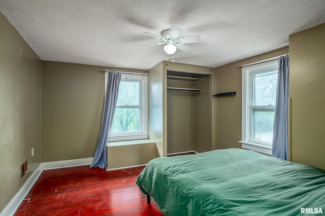 bedroom featuring visible vents, a textured ceiling, wood finished floors, and multiple windows