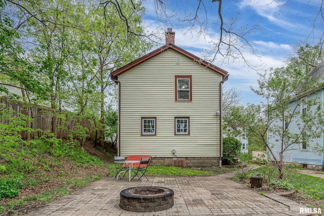 back of property featuring a patio, fence, a chimney, and an outdoor fire pit