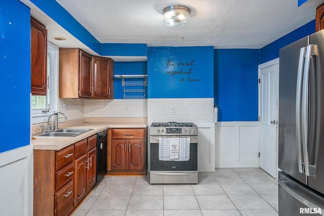 kitchen with light countertops, a sink, backsplash, light tile patterned floors, and stainless steel appliances