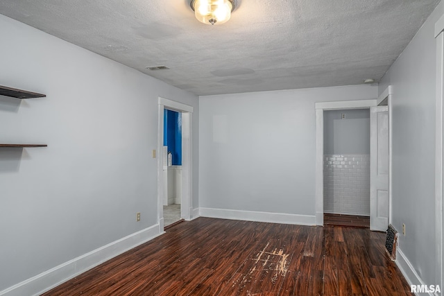 unfurnished bedroom featuring baseboards, a textured ceiling, visible vents, and wood finished floors