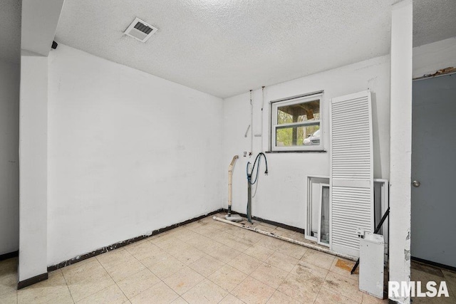 unfurnished room featuring visible vents, a textured ceiling, and baseboards