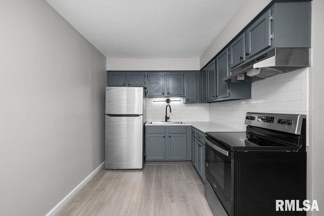 kitchen featuring range with electric cooktop, a sink, baseboards, freestanding refrigerator, and under cabinet range hood