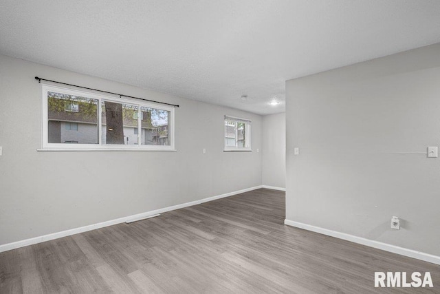 spare room with baseboards and wood finished floors