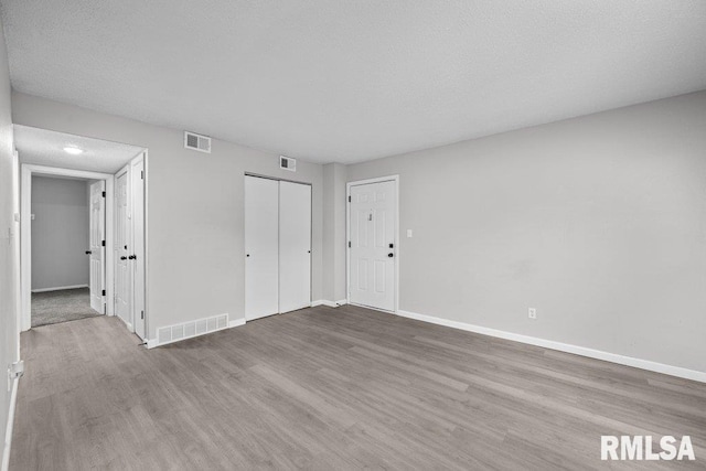 unfurnished bedroom featuring baseboards, visible vents, and wood finished floors